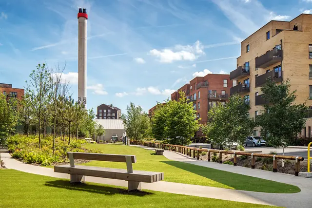Landscaped gardens and seating at Eastman Village, with the former factory chimney behind