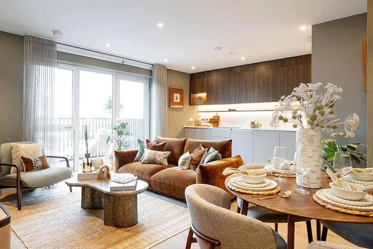 Two-bedroom show home at Bow Green: round dining table, sofa and armchair by tall windows