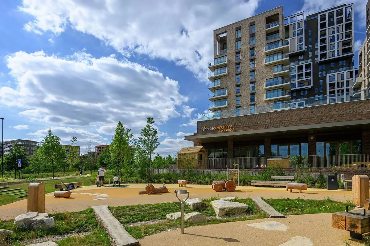 Kidbrooke Village’da zemin katında kreş bulunan apartman binaları ve önündeki peyzajlı oyun alanı.