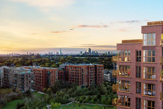 Kidbrooke Village’daki Skyview Gardens’tan apartman binaları ve park alanı üzerinden Londra merkezinin siluetine doğru gün batımı görünümü.