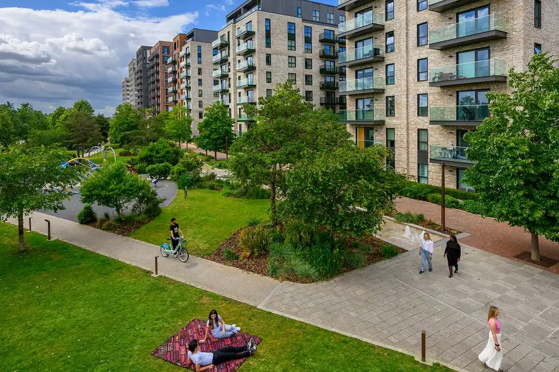 Apartment buildings beside a landscaped park with lawns, a play area and paths at The Green Quarter.