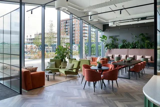 A glazed lobby lounge with armchairs, sofas and dining tables at The Green Quarter.