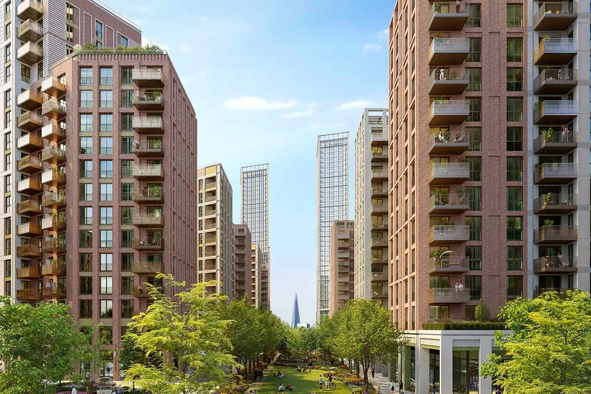 Brick apartment buildings with balconies on both sides of a tree-lined park at TwelveTrees Park, with taller towers in the distance.