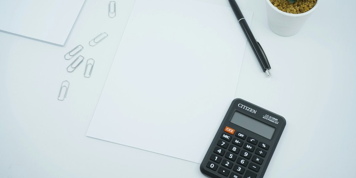 A black calculator and a pen on a sheet of white paper