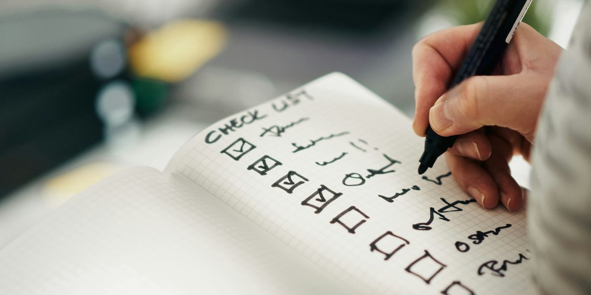 A hand ticking items off a handwritten checklist