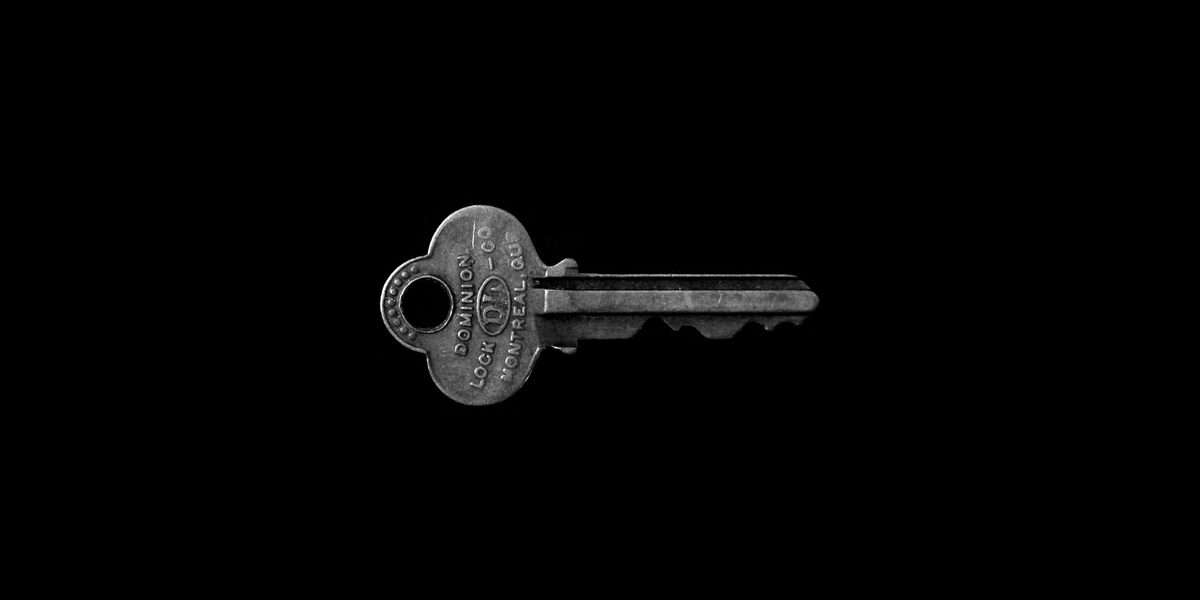 An old metal door key against a black background