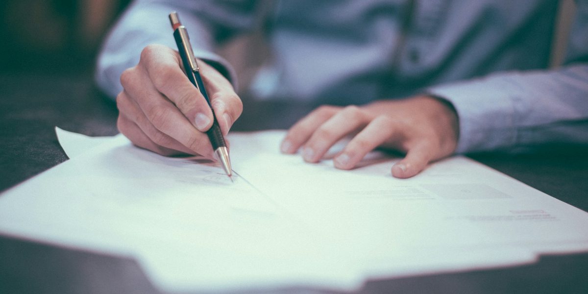 A person signing a printed document with a pen