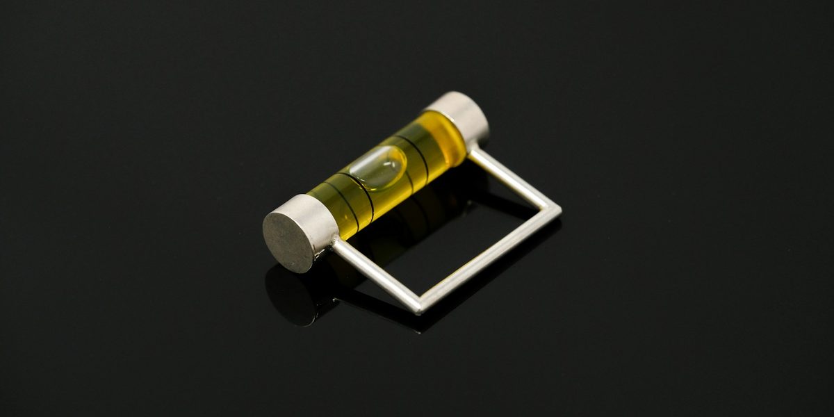 A yellow spirit level vial with a metal frame on a glossy black surface