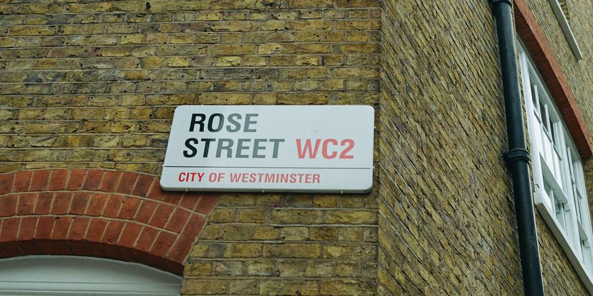 A City of Westminster street sign for Rose Street WC2 on a brick wall