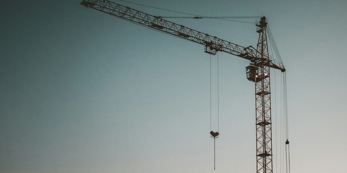 A single tower crane against a pale sky, with no building in view